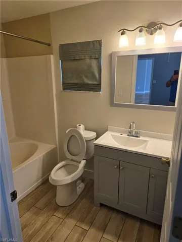 Bathroom featuring wood finished floors, vanity, and washtub / shower combination
