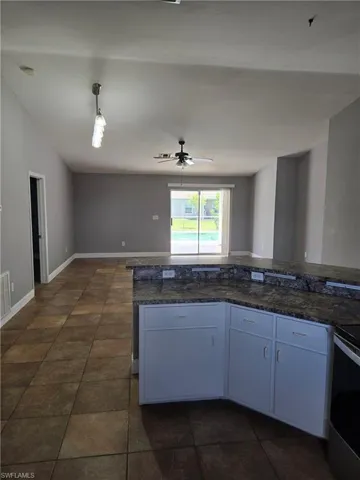 Kitchen with electric range oven, a ceiling fan, open floor plan, and dark tile patterned floors