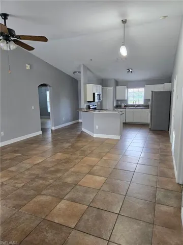 Kitchen with stainless steel appliances, arched walkways, open floor plan, ceiling fan, and white cabinets