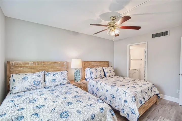 Bedroom with ensuite bath, a ceiling fan, and wood finished floors