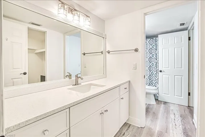 Full bath with vanity, a shower with shower curtain, and light wood finished floors