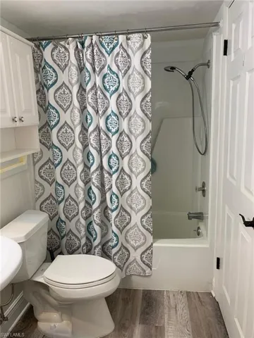 Full bathroom featuring dark wood-style flooring and shower / bath combo