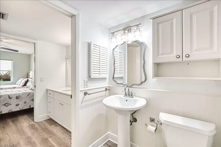 Ensuite bathroom featuring light wood finished floors and wainscoting
