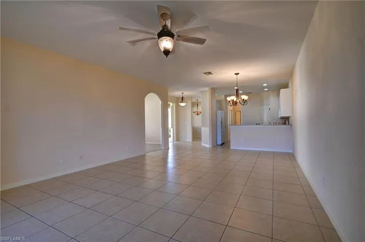 Spare room with ceiling fan, suspended lighting, light tile patterned floors, and arched walkways