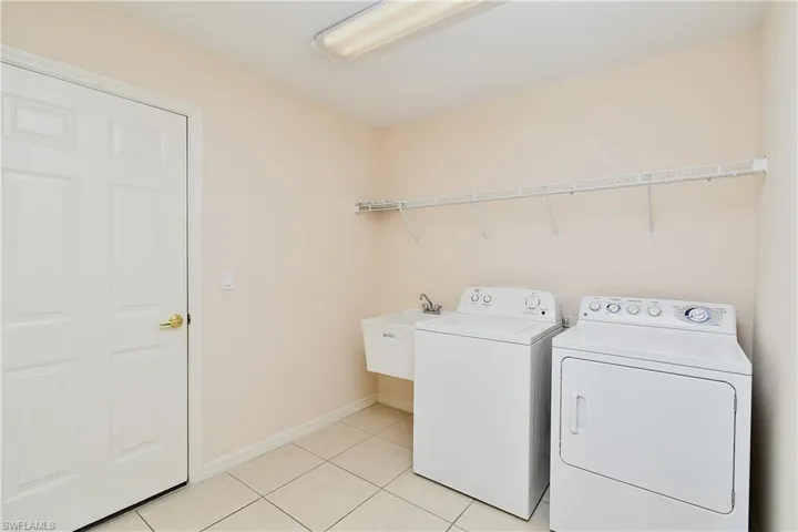 Laundry area with washer and clothes dryer and light tile patterned floors