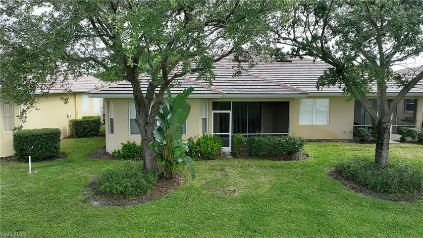 Rear view of house with a sunroom, stucco siding, a lawn, and a tile roof