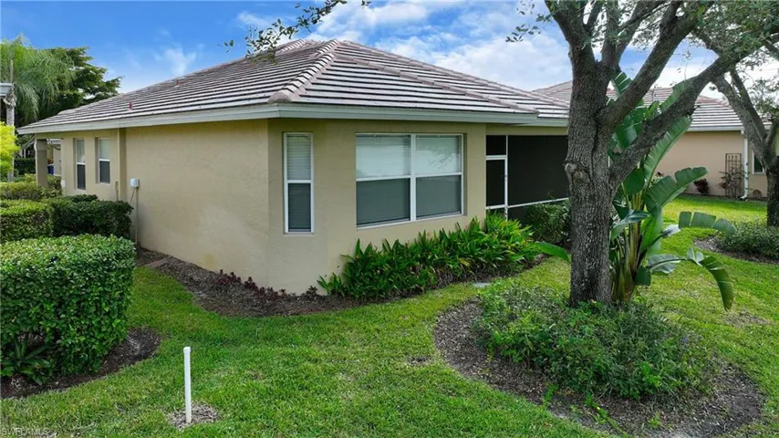View of property exterior featuring stucco siding, a lawn, a tile roof, and a sunroom