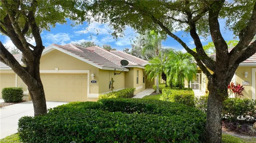 Ranch-style home with an attached garage, driveway, stucco siding, and a tile roof