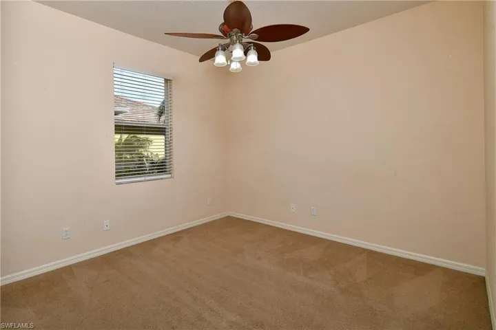 Carpeted spare room featuring baseboards and a ceiling fan