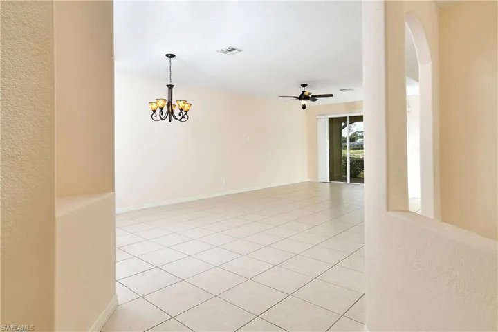 Spare room with light tile patterned floors, suspended lighting, ceiling fan, and a textured wall