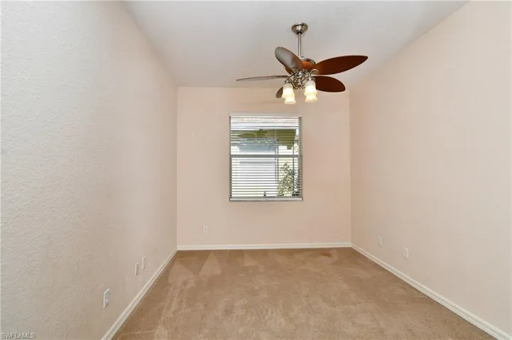 Spare room featuring ceiling fan, a textured wall, and light carpet