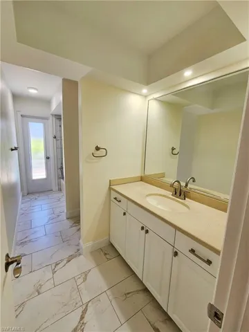 Bathroom with light marble finish floors, vanity, and shower / bath combination