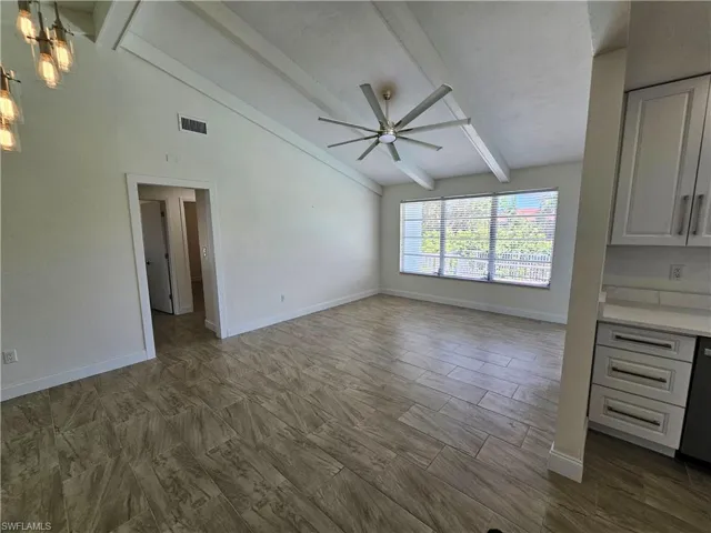 Unfurnished living room with beamed ceiling, ceiling fan, and high vaulted ceiling