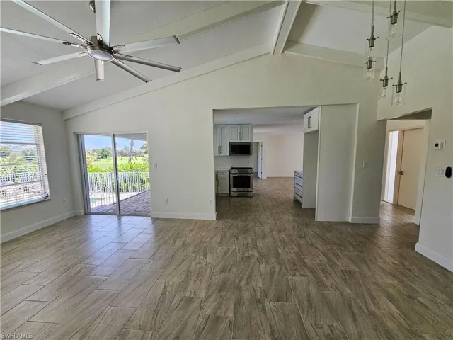 Unfurnished room featuring beamed ceiling, wood finish floors, a ceiling fan, and high vaulted ceiling