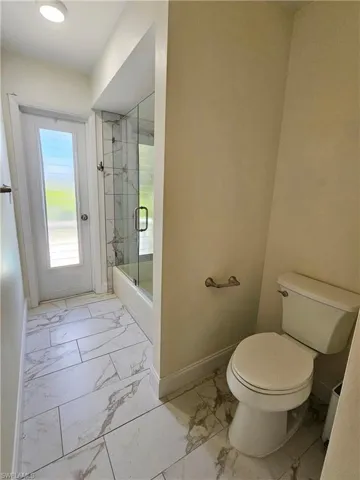 Bathroom featuring light marble finish flooring and an enclosed shower