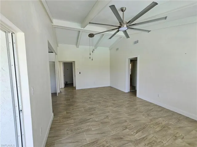 Spare room with beamed ceiling, ceiling fan, and high vaulted ceiling