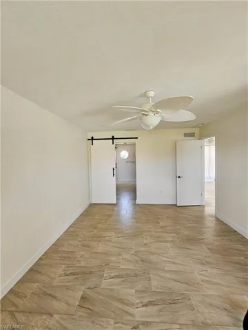 Unfurnished bedroom featuring a barn door and a ceiling fan