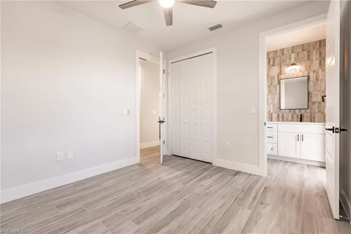Unfurnished bedroom featuring ceiling fan, a closet, sink, light hardwood / wood-style floors, and ensuite bathroom