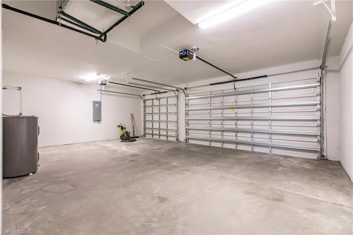 Garage with a garage door opener, electric panel, and water heater