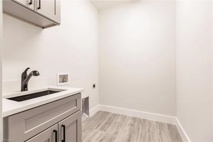 Laundry room with sink, cabinets, hookup for a washing machine, light hardwood / wood-style floors, and electric dryer hookup
