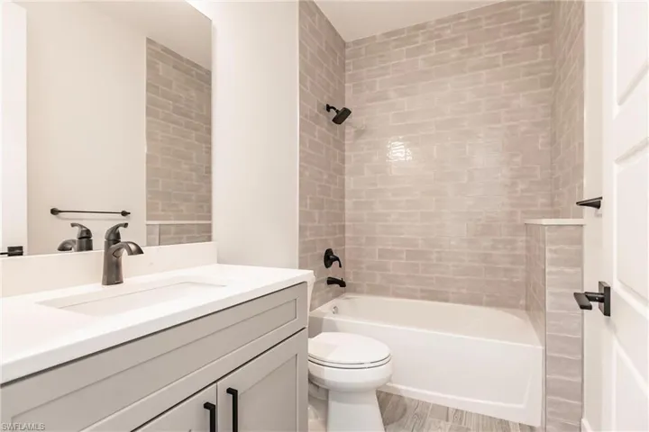 Full bathroom featuring hardwood / wood-style flooring, toilet, vanity, and tiled shower / bath combo