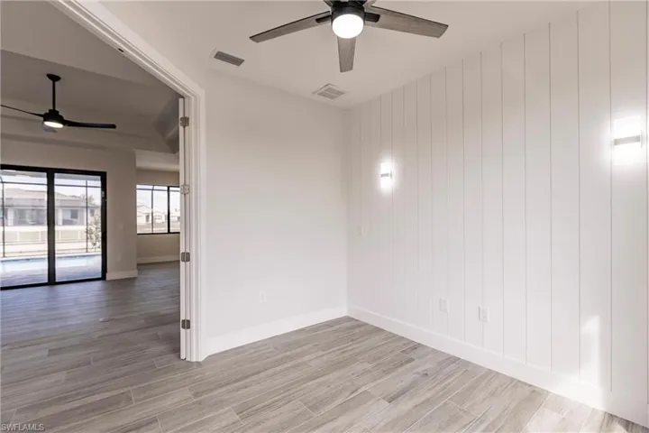Unfurnished room with ceiling fan, wood walls, and light hardwood / wood-style floors