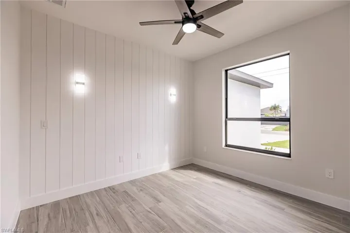 Spare room with ceiling fan, wood walls, and light hardwood / wood-style floors