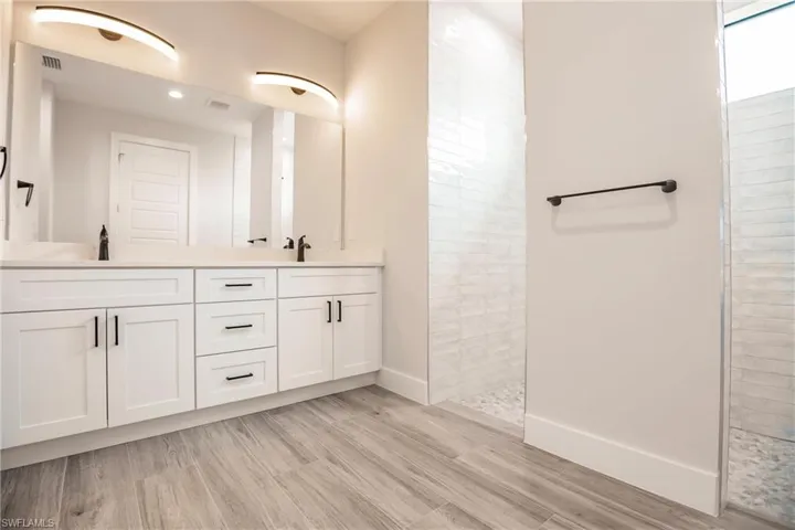 Bathroom featuring wood-type flooring, walk in shower, and vanity