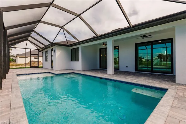 View of swimming pool featuring a lanai, ceiling fan, and a patio area