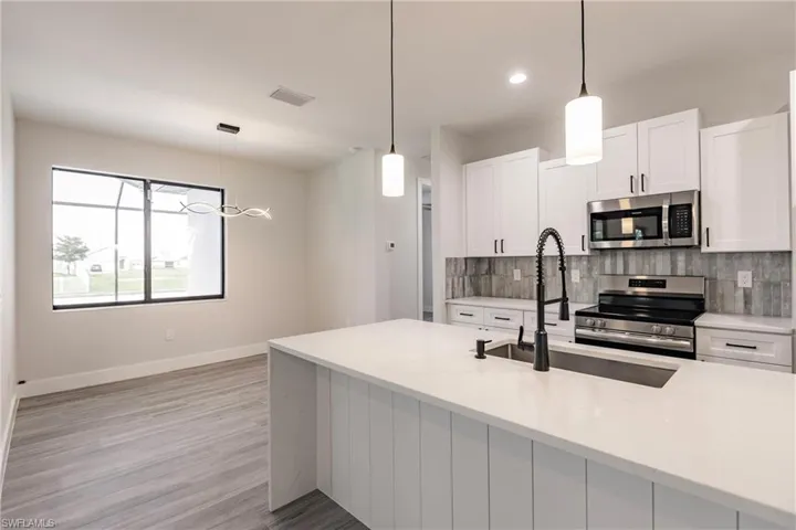 Kitchen featuring pendant lighting, appliances with stainless steel finishes, and white cabinetry