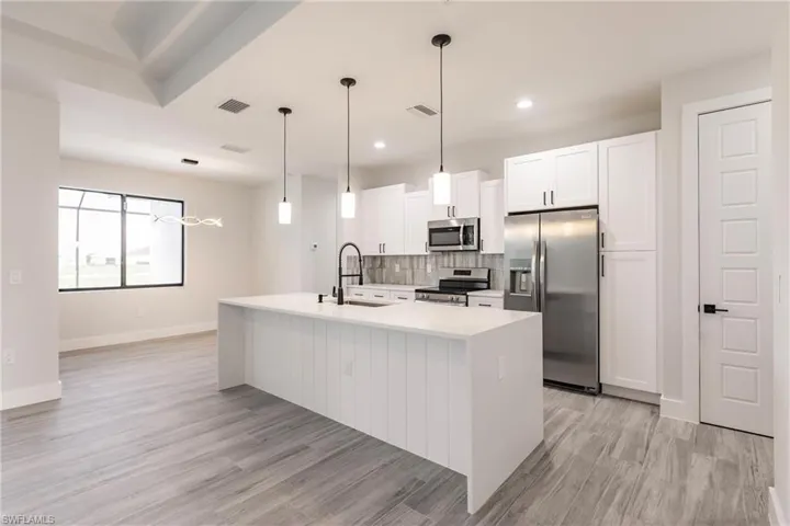 Kitchen featuring a center island with sink, appliances with stainless steel finishes, light hardwood / wood-style floors, and white cabinetry