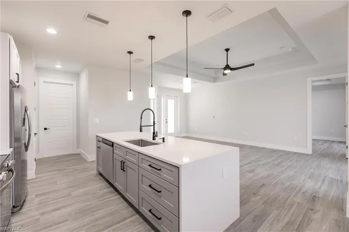 Kitchen with appliances with stainless steel finishes, light hardwood / wood-style flooring, a center island with sink, and sink