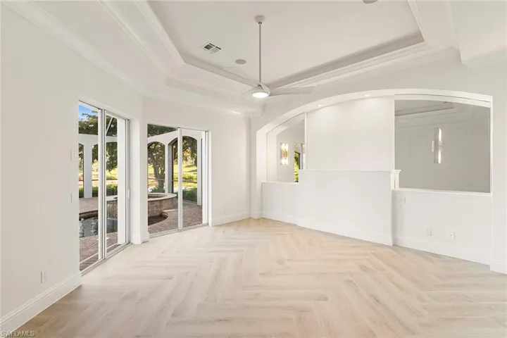Primary Bedroom features Ashford porcelain Honey Blonde Oak tile with dual patio sliding doors out to the lanai and pool with spa