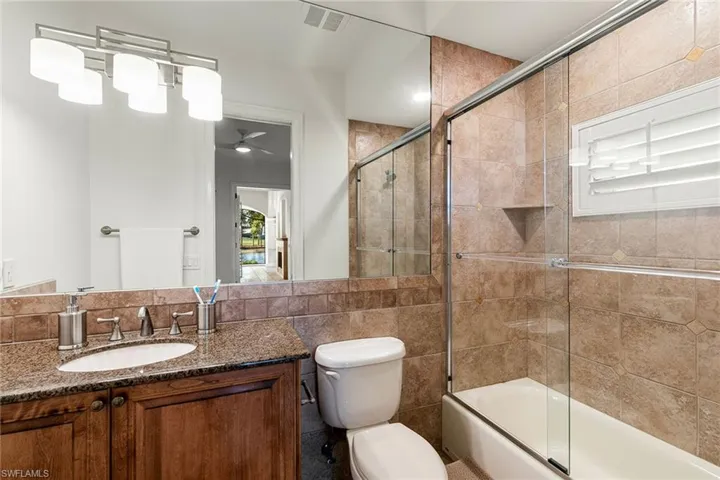 Full ensuite bathroom featuring a porcelain  tile finish shower with bath and granite top vanity