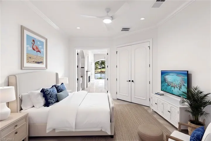 Spacious ensuite bedroom with Ashford porcelain Honey Blonde Oak tile with french door access to the lanai | Shown with virtually staged furnishings for design inspiration