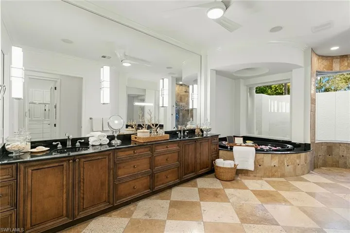 Primary bathroom with jetted bath, marble finish shower, double vanity, and recessed lighting.