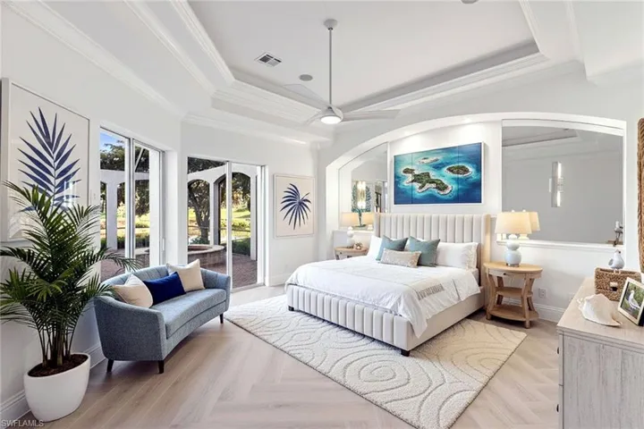 Primary Bedroom features Ashford porcelain Honey Blonde Oak tile with dual patio sliding doors out to the lanai. | Shown with virtually staged furnishings for design inspiration