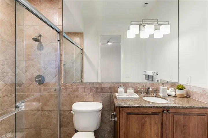 Full ensuite bathroom featuring a porcelain  tile finish shower and granite top vanity