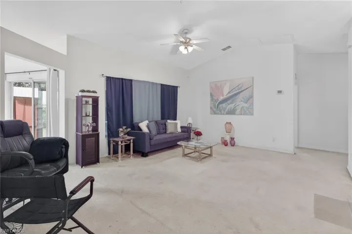 Living room featuring light carpet, ceiling fan, and lofted ceiling