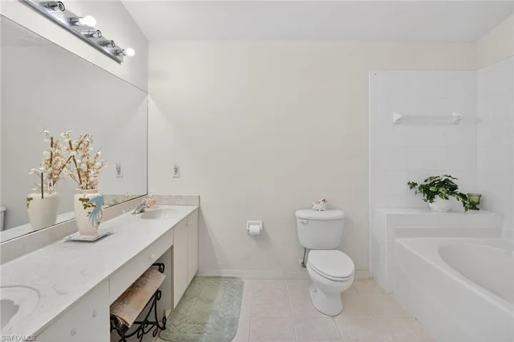 Bathroom with double vanity, a tub, and light tile patterned floors