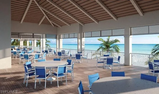 Expansive covered dining pavilion with soaring wood-beam ceiling, floor-to-wall glass panels, and wood-finish decking overlooking oceanfront scenery