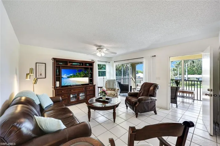 Living room featuring ceiling fan, light tile patterned floors, and a textured ceiling
