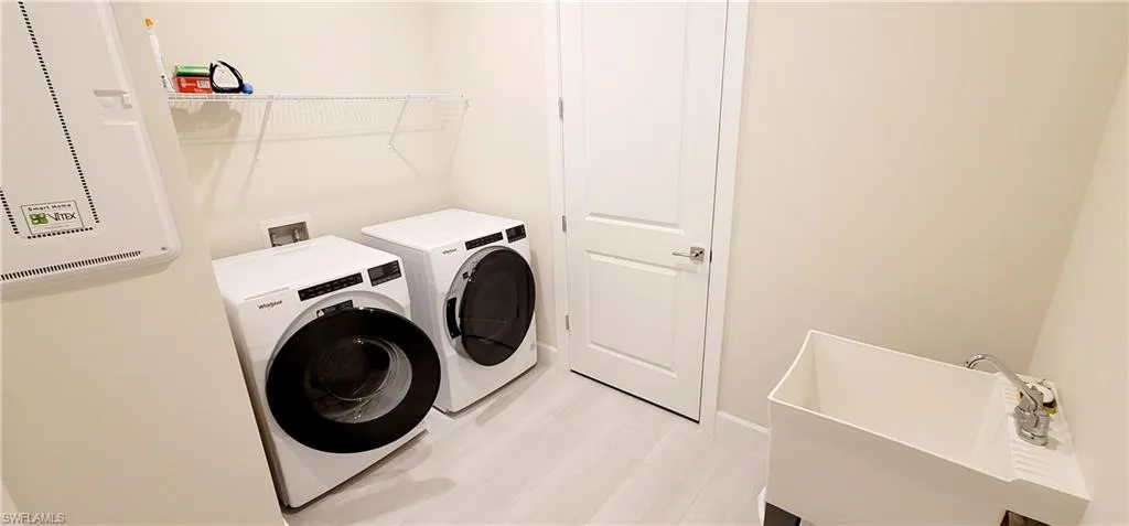 Laundry room featuring separate washer and dryer, light hardwood / wood-style floors, and sink