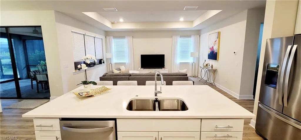 Kitchen with stainless steel appliances, sink, a center island with sink, light hardwood / wood-style flooring, and white cabinetry