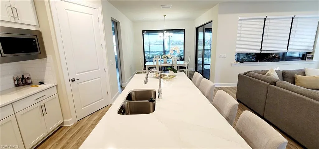 Dining area with sink, light hardwood / wood-style floors, and a notable chandelier