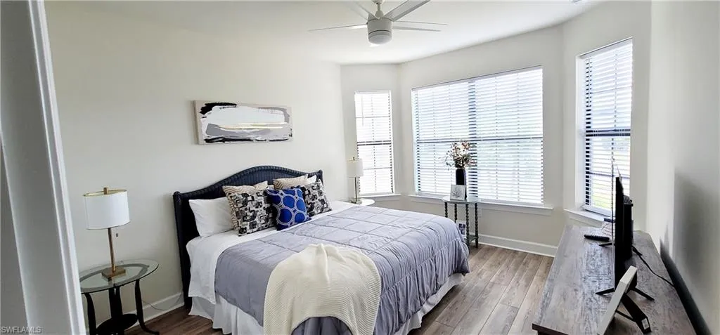 Bedroom with light wood-type flooring, multiple windows, and ceiling fan
