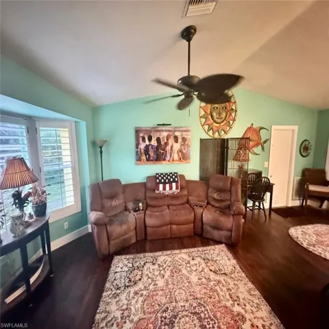 Living room featuring vaulted ceiling, ceiling fan