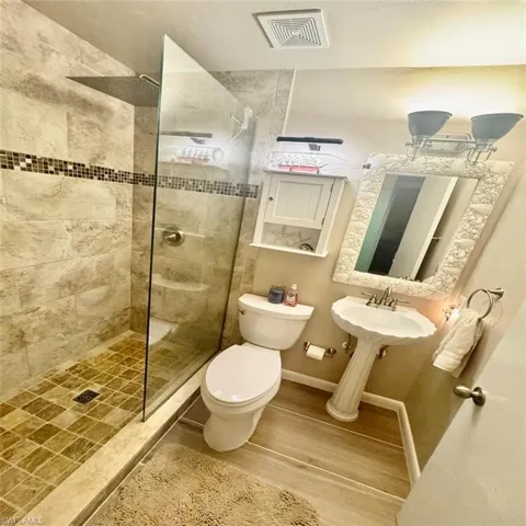 Bathroom with a tile shower, hardwood / wood-style floors, sink, and toilet