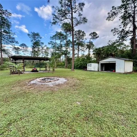 View of yard featuring oversized shed and pole barn and outdoor fire pit
