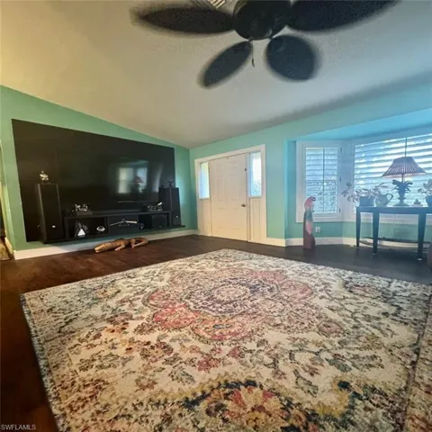 Living room featuring luxury vinyl flooring, vaulted ceiling, ceiling fan, and a textured ceiling